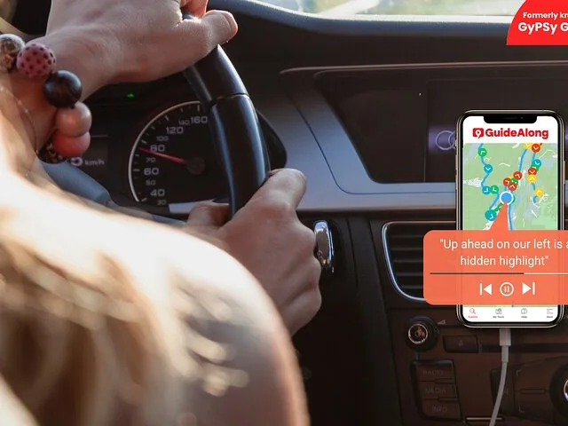 Person driving a car using a GPS audio guide app