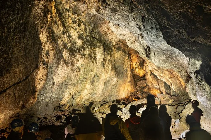 Silhouettes of people looking at the textured rock walls inside Vatnshellir Cave.