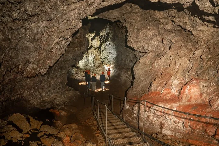 Tour guide and visitors exploring the rocky interior of Vatnshellir Cave.