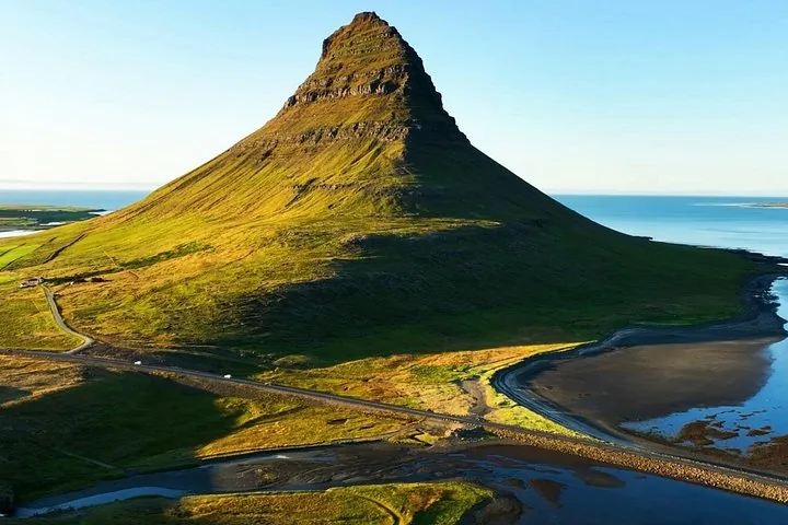 Kirkjufell mountain rising above coastal landscape with roads and water