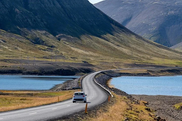 White car driving on a scenic coastal road in Iceland