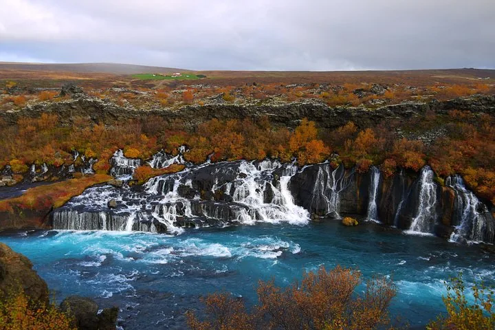 Hraunfossar waterfall flowing into a blue river surrounded by autumn colors