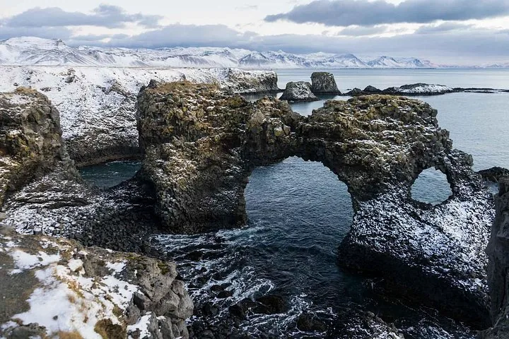 Gatklettur rock arch in the ocean at Arnarstapi with snow